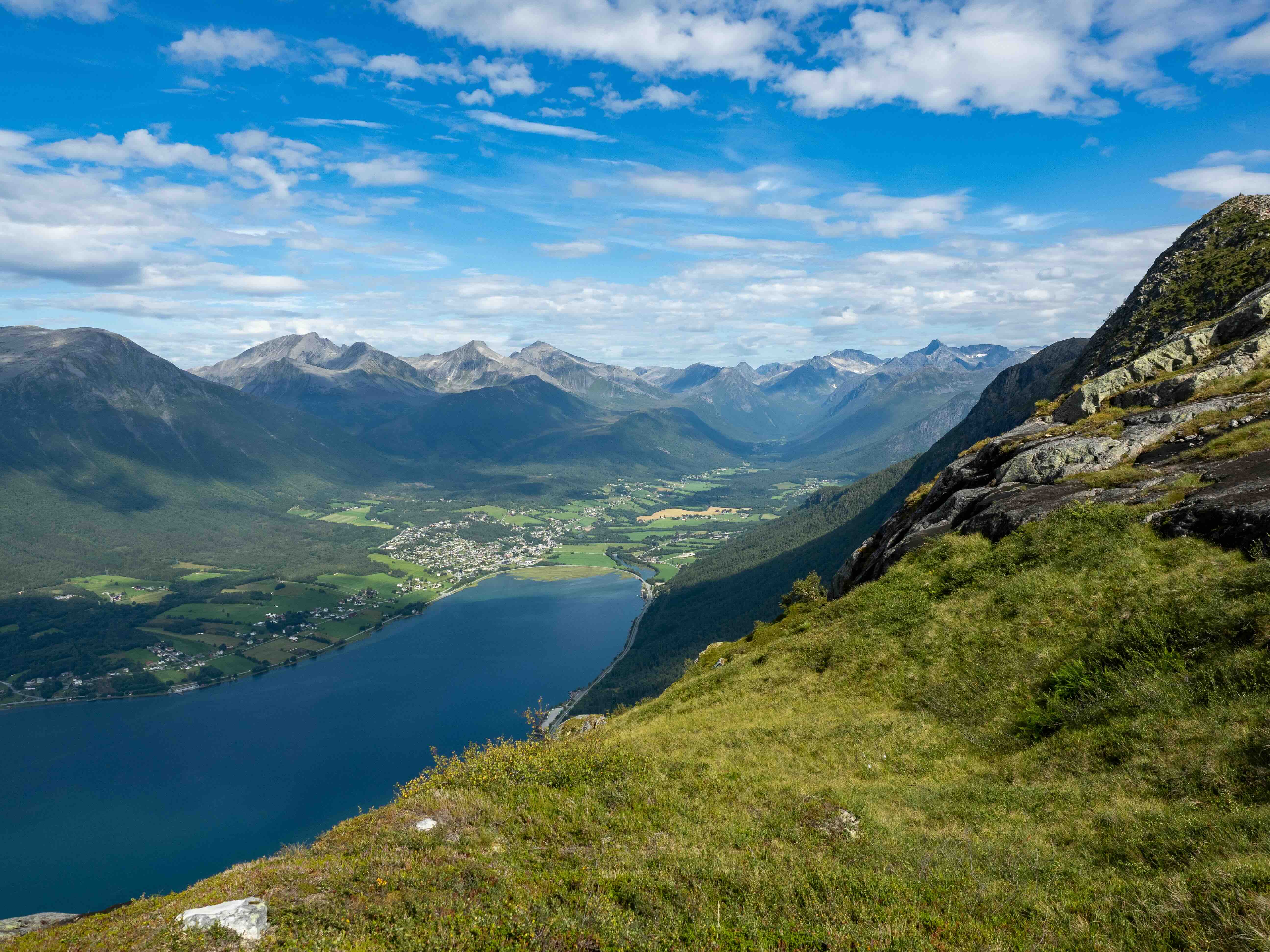 Rauma Railway train curving through the Romsdal valley beneath steep mountain walls toward Åndalsnes in Norway