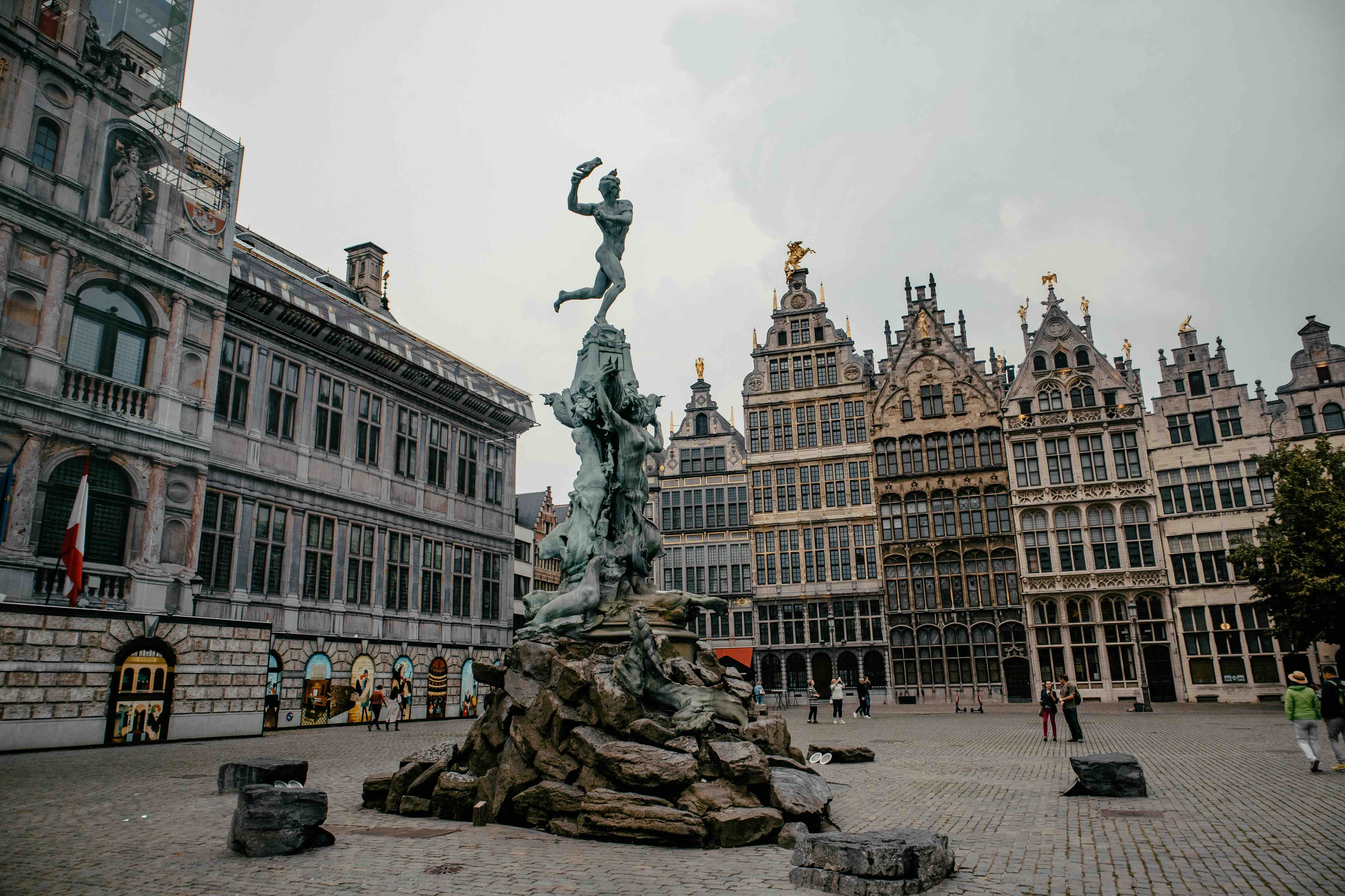 The bronze Brabo Fountain on Antwerp's Grote Markt, the figure of Silvius Brabo hurling a severed hand, with the Renaissance city hall on the left and the row of gilded step-gabled guildhalls behind