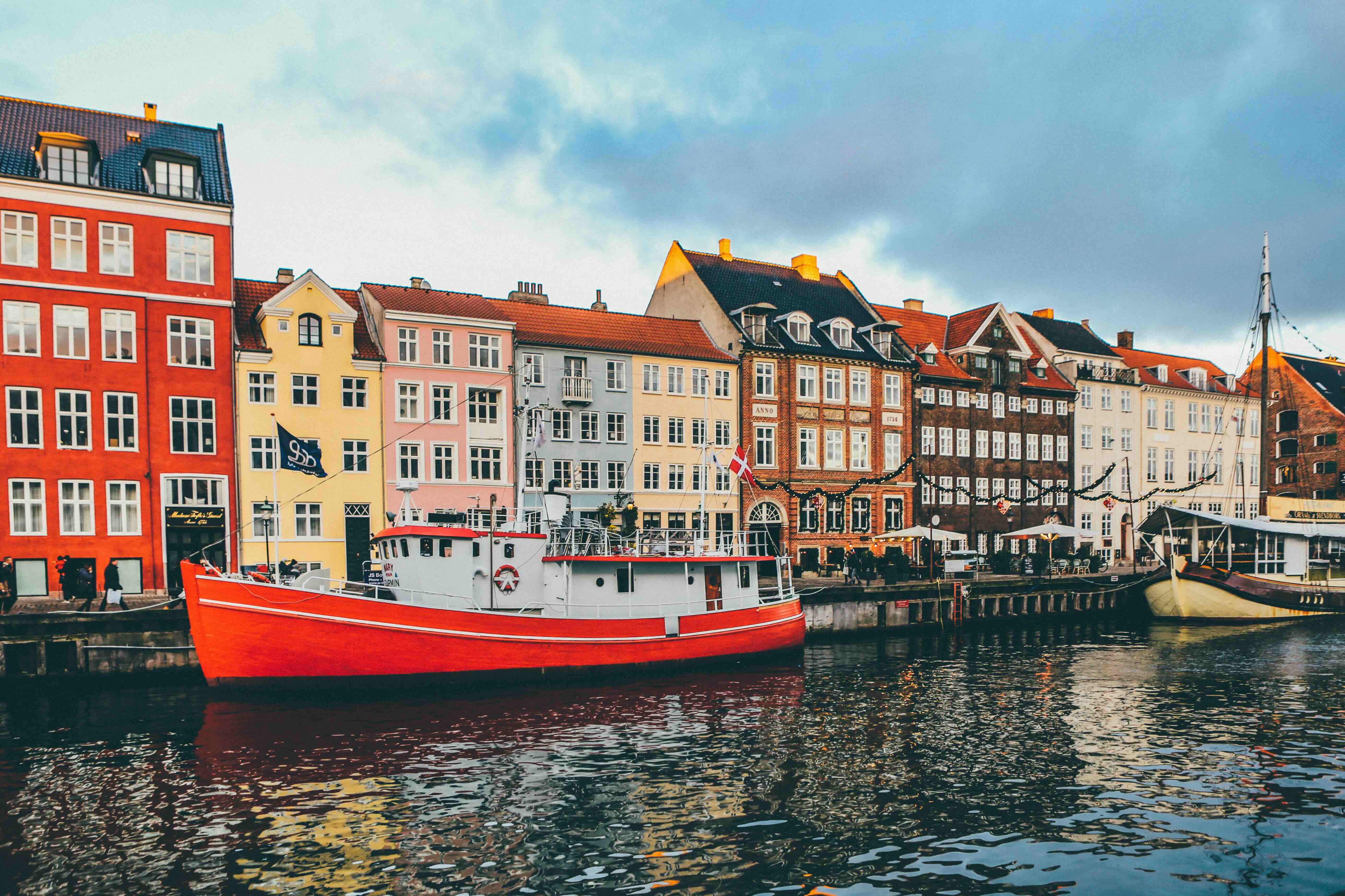 The colourful waterfront townhouses and moored boats of Copenhagen reflected in a canal, a classic view of the Danish capital