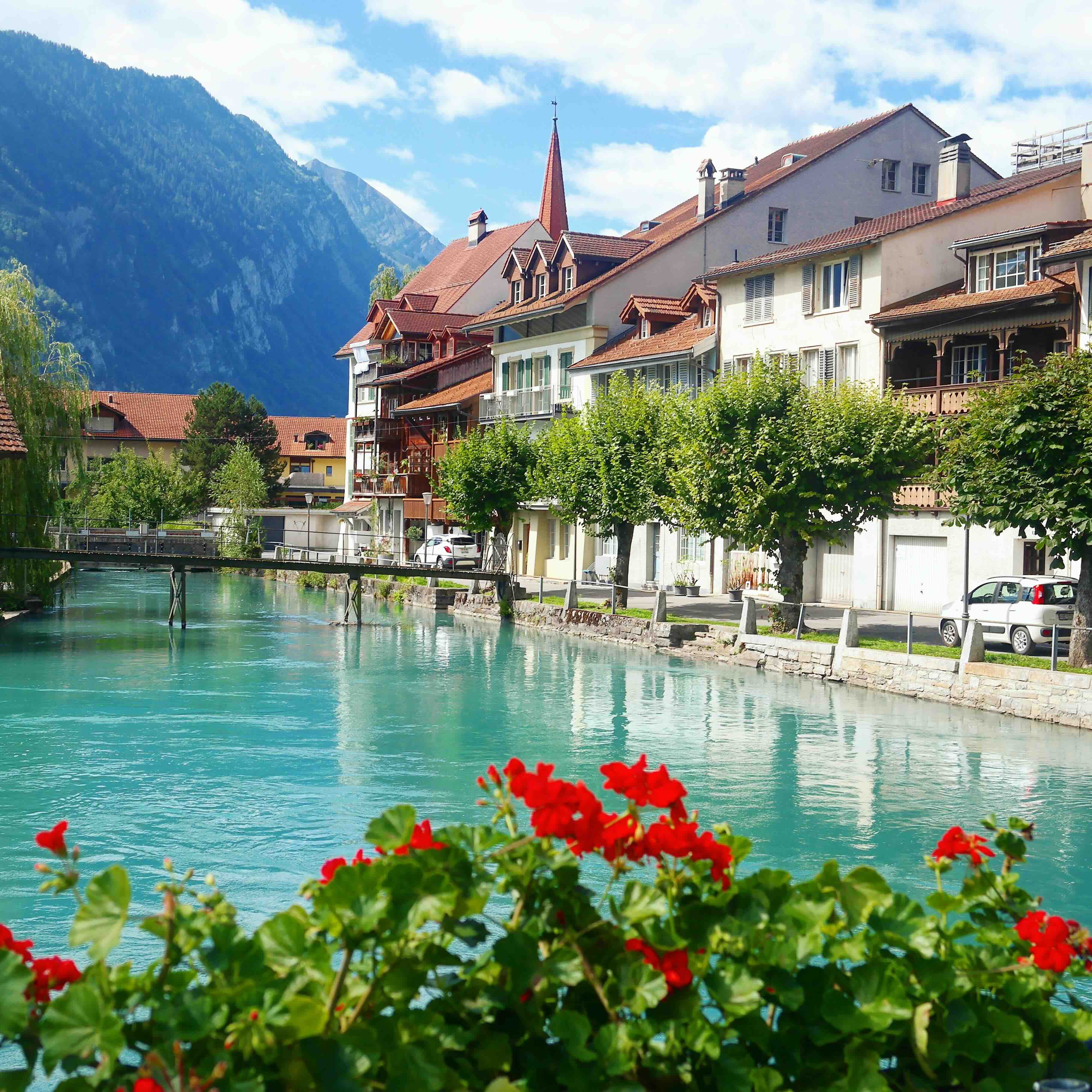 The turquoise Aare river and timber houses of Interlaken's old quarter with Alpine peaks behind