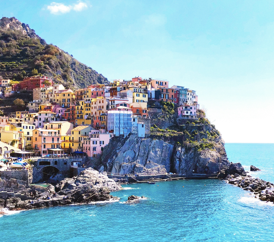 The painted houses of Manarola stacked above the harbour in the Cinque Terre
