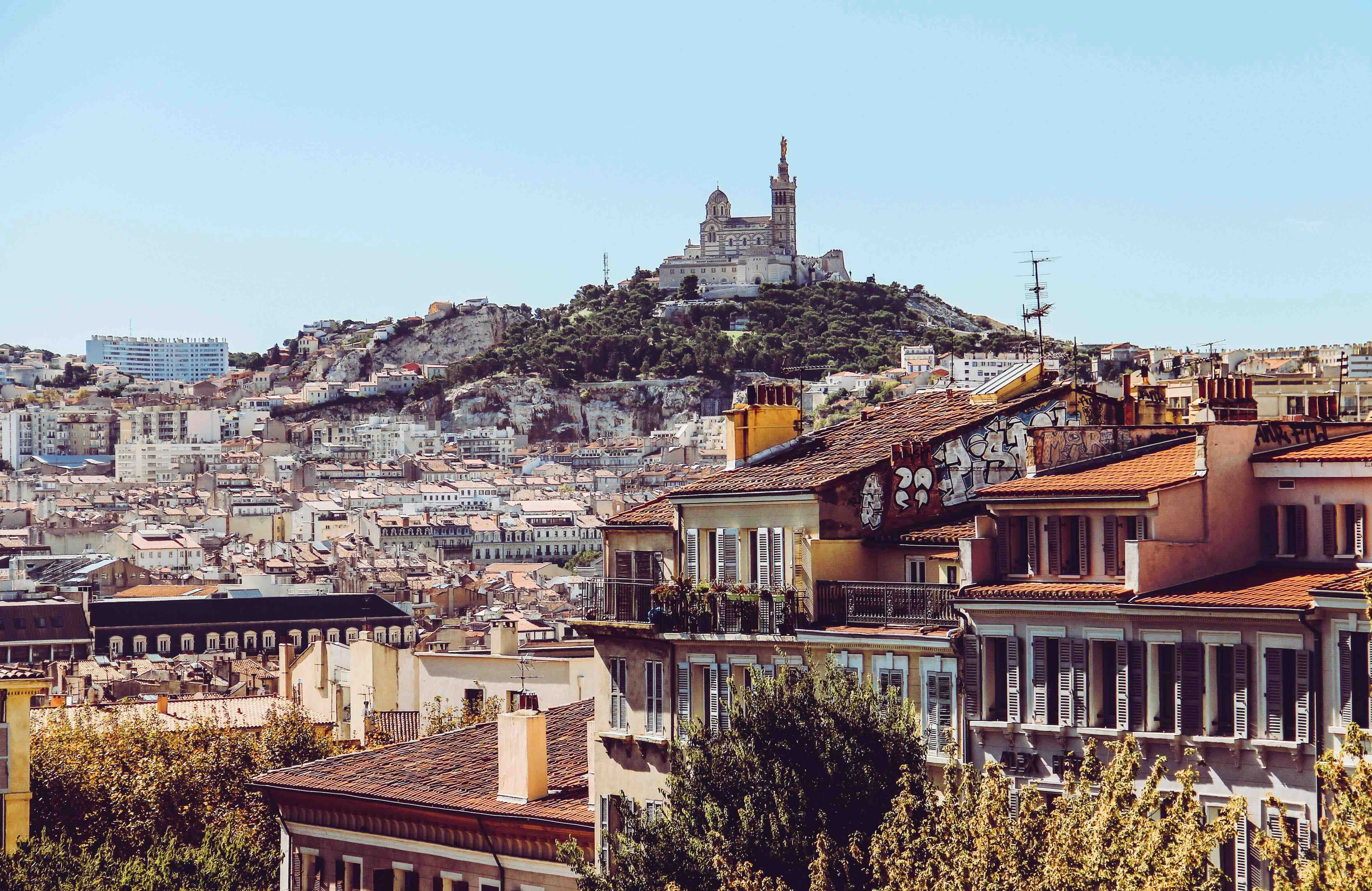 The terracotta rooftops of Marseille with the basilica of Notre-Dame de la Garde on the hill above