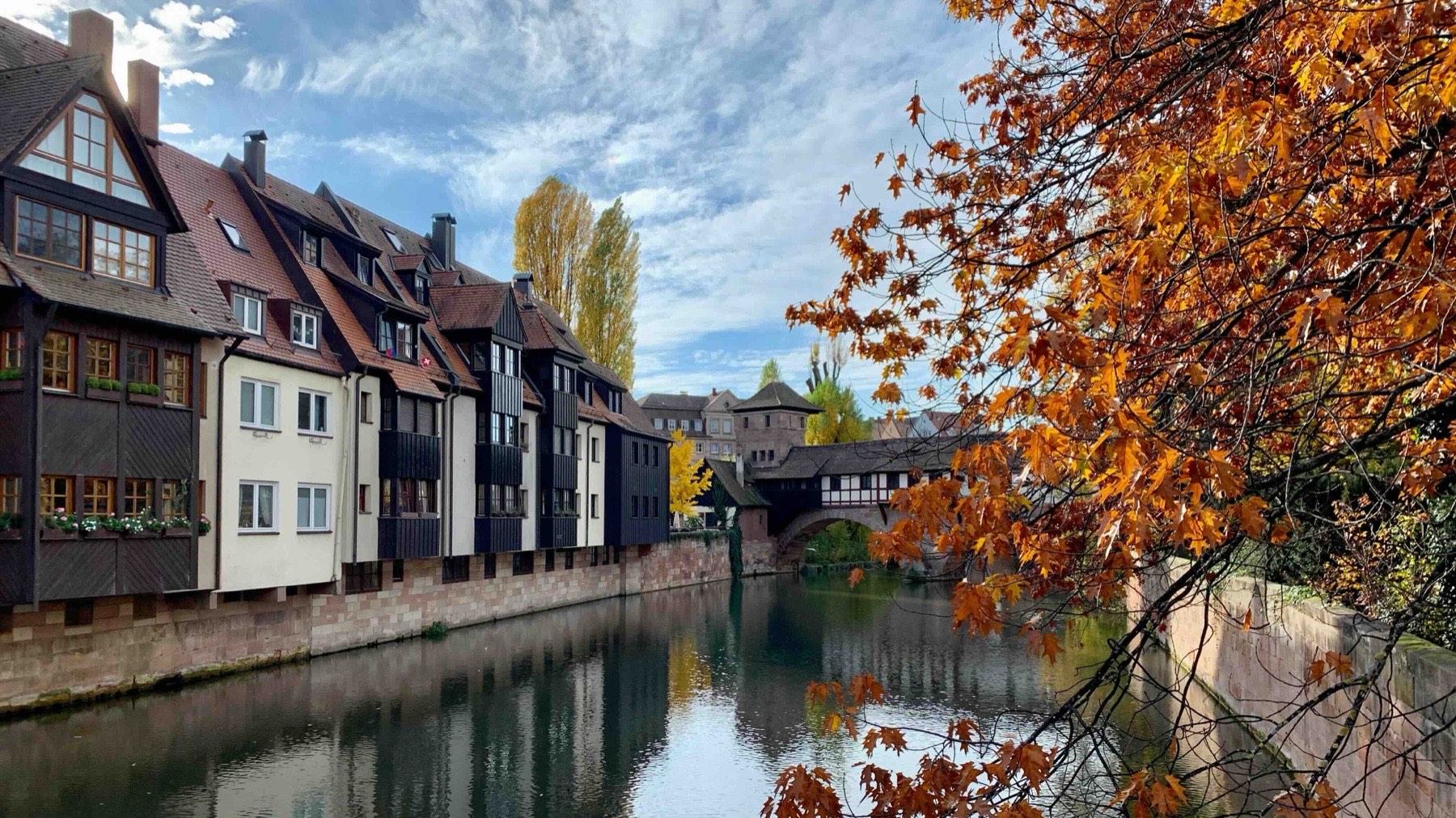 The half-timbered houses and sandstone bridge over the Pegnitz river in the old town of Nuremberg, with the castle beyond