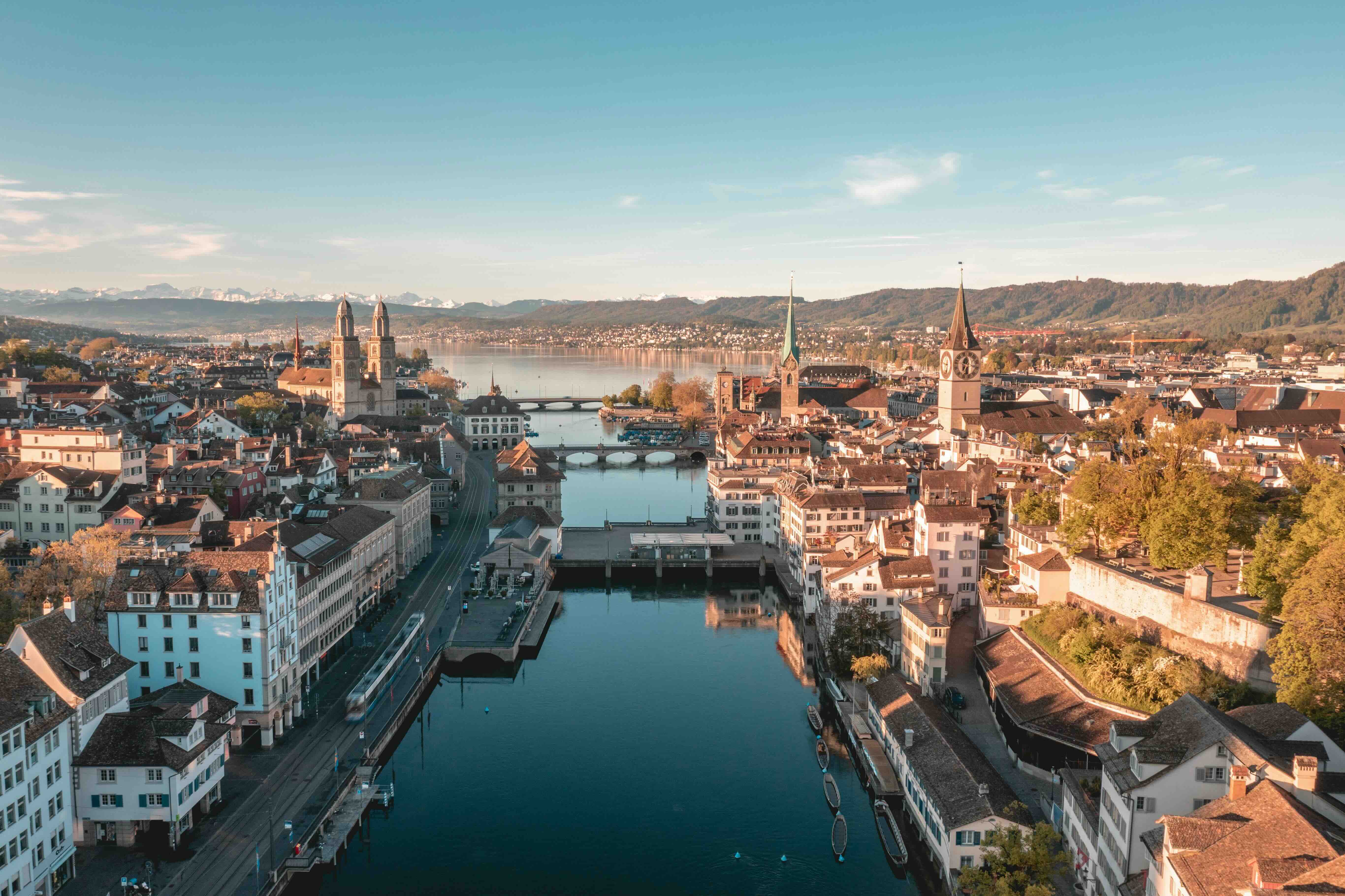 The Limmat river and church spires of Zurich's old town with Lake Zurich and the Alps behind